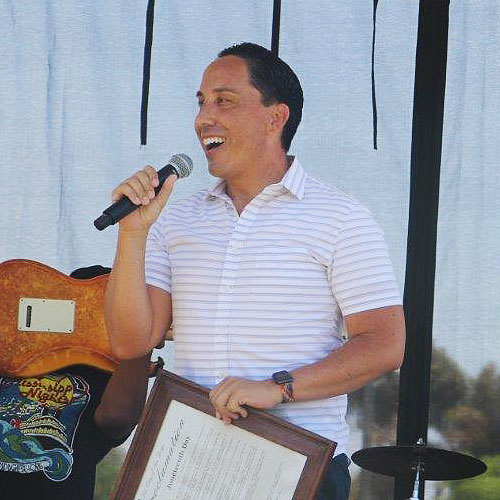 Mayor Todd Gloria presenting a plaque on a stage