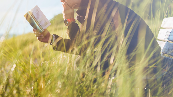 A person reading book on a bench.