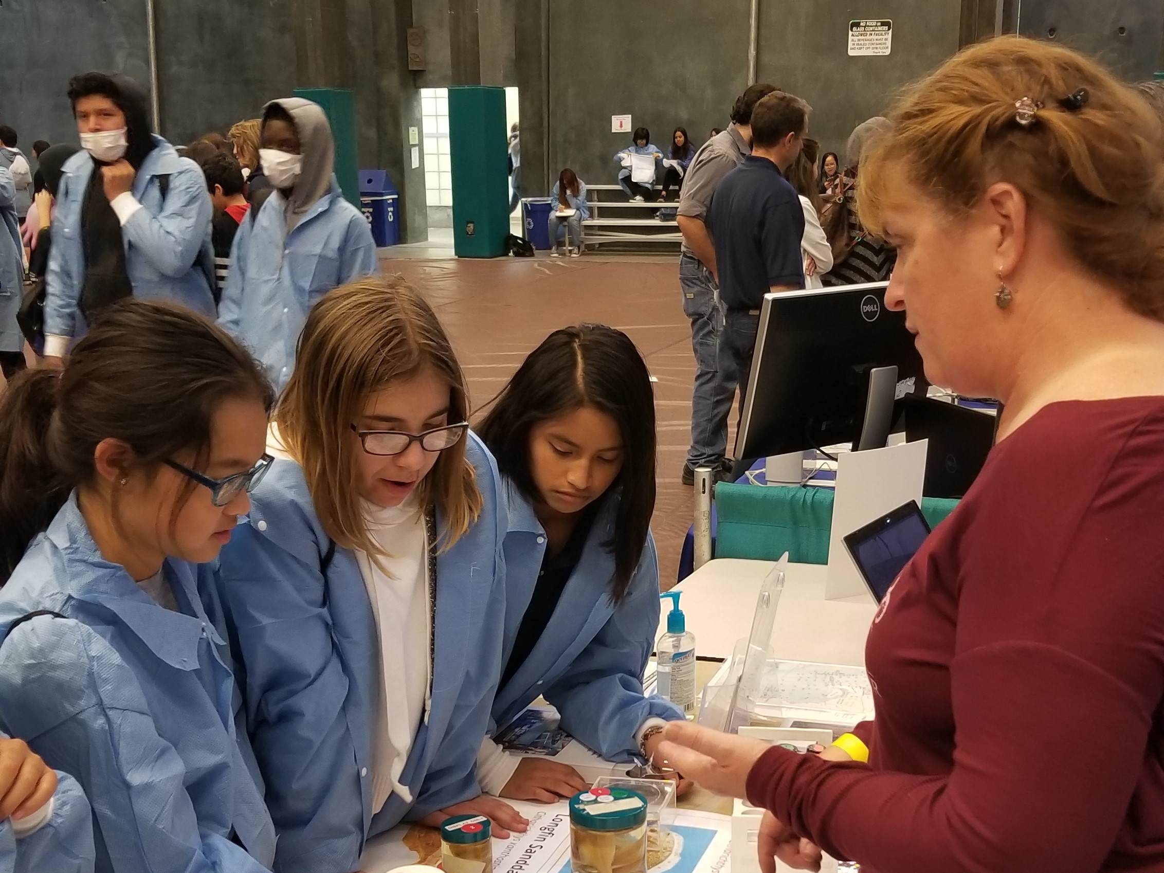 A marine biologist shows students examples of animals monitored as part of the City's Ocean Monitoring Program at a High Tech Fair.