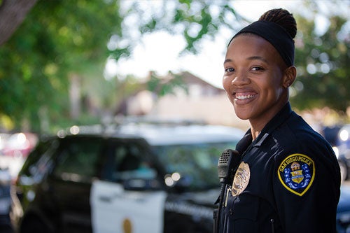 Smiling Police Recruiter standing in front of a police car