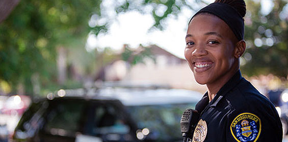 Smiling police officer standing in front of a police car