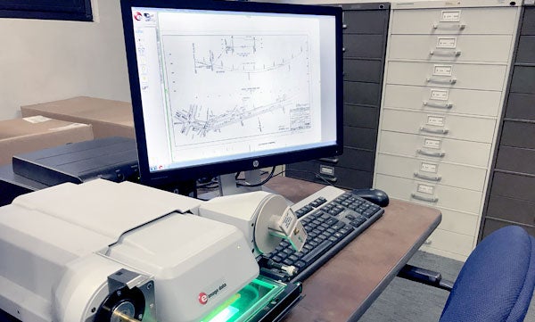 A computer showing a microfiche slide with drawers in the background