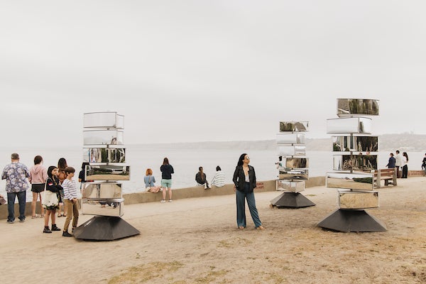 Park visitors interacting with periaktois that are composed of independently rotating mirrored sections