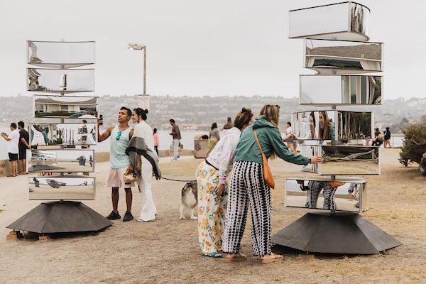 Park visitors interacting with periaktois that are composed of independently rotating mirrored sections