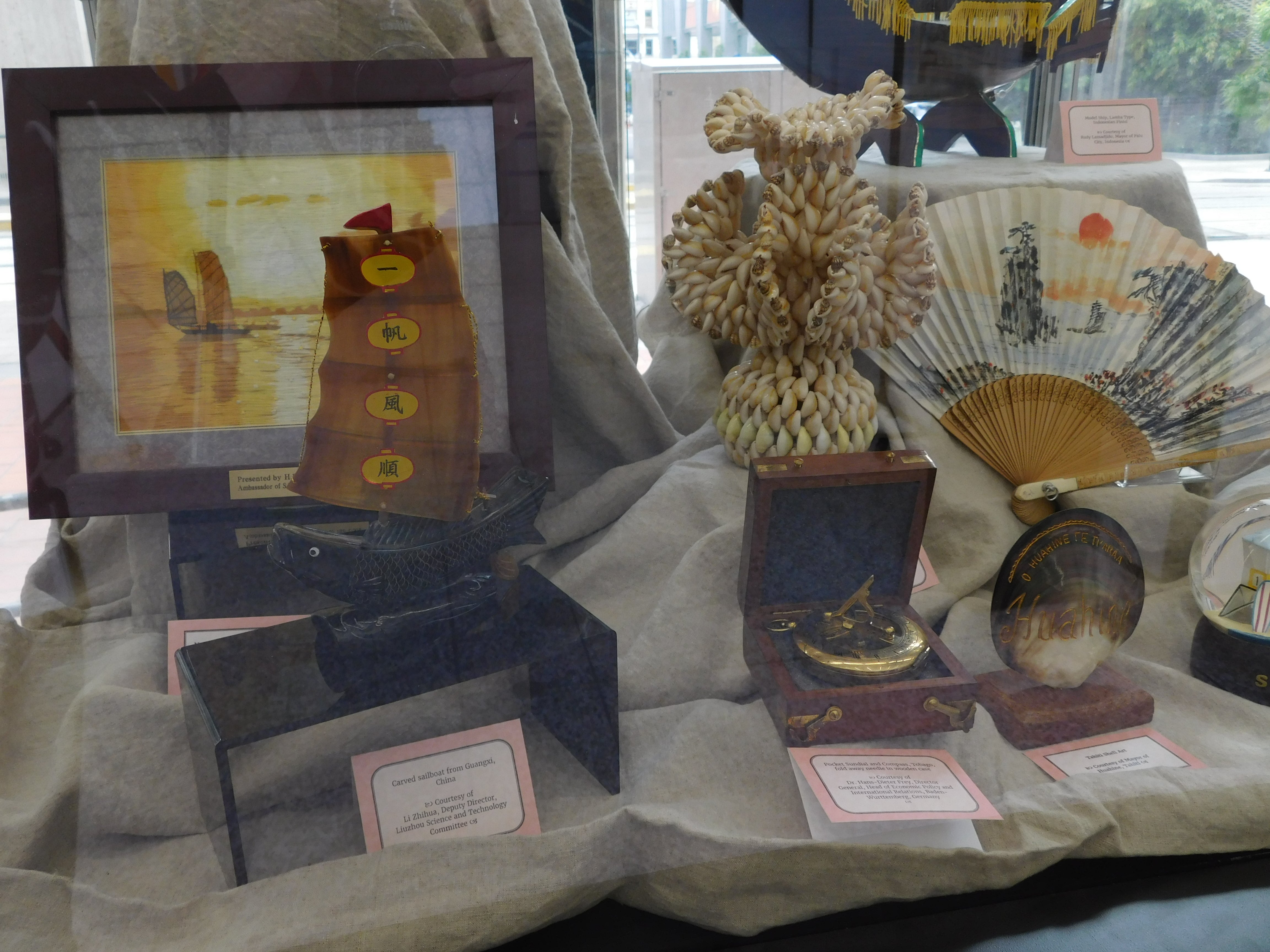 Embroidered image of ships&#44; Chinese ship carved from shells&#44; brass compass&#44; shell vase and shell scuplture.