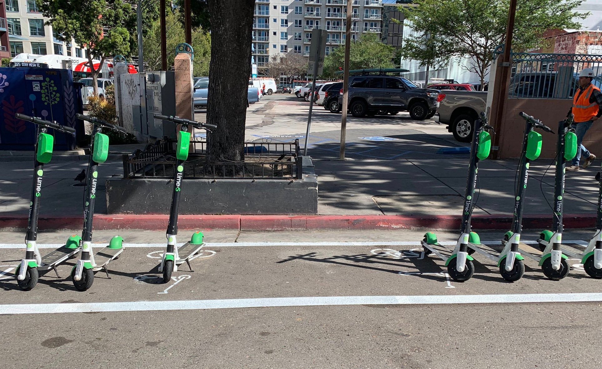 Dockless bikes parked in a dedicated scooter corral on a street.