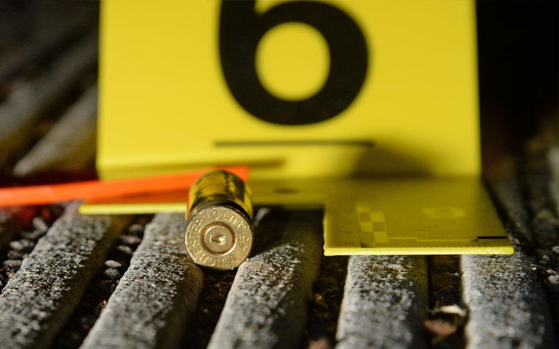 An evidence marker next to a bullet casing on the ground