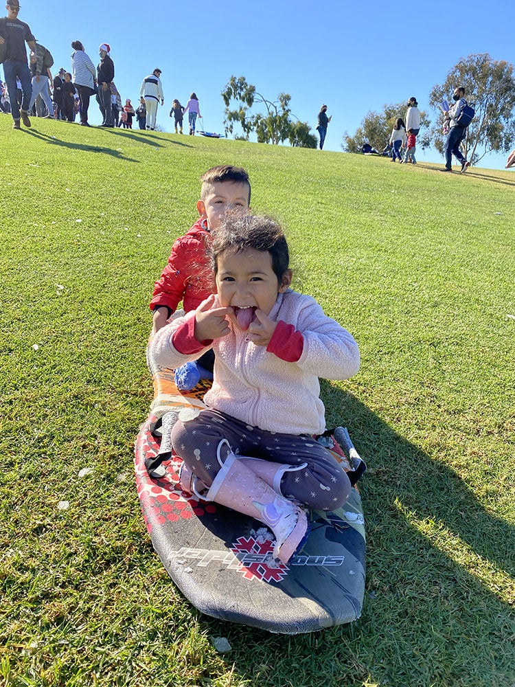 photo of two children sledding down a  hill