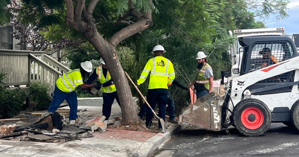 five city employees working to fix a section of sidewalk