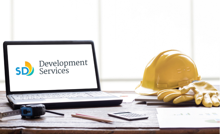 The City of San Diego Development Services Department logo displayed on a laptop, sitting on top of a table. 