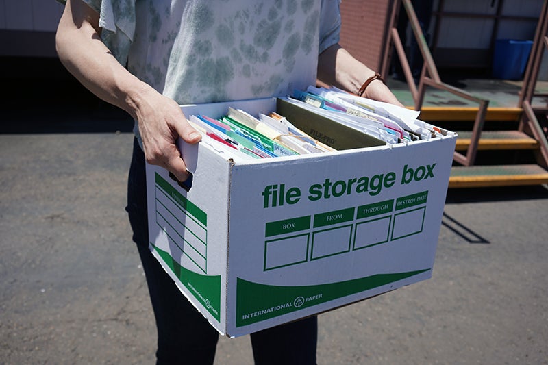 A person carrying an open file storage box