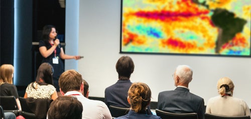 A presenter speaking about El Niño to a group of business professionals