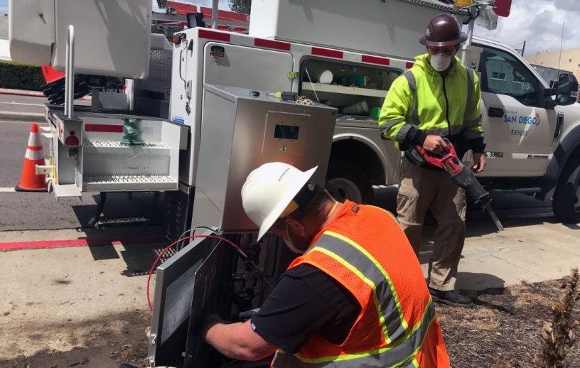 City electricians working on a panel on the side of a street