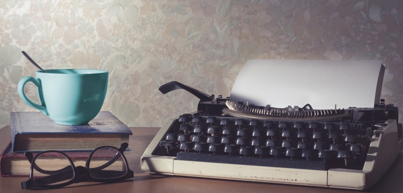 Typewriter with blue cup on desk