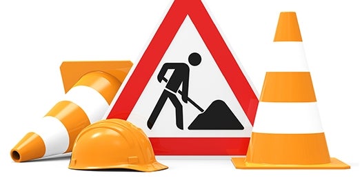 Construction cones, hard hat and a sign showing construction work.