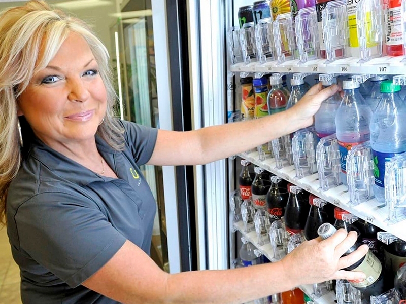 woman standing in front of case with beverages
