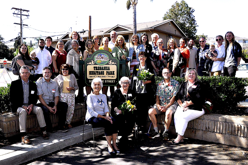A large group of smiling people gathered around the Treganza Heritage Park sign
