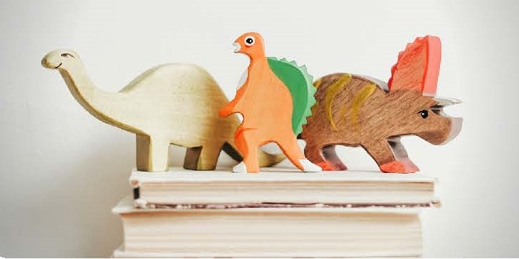 Wooden dinosaurs on top of books