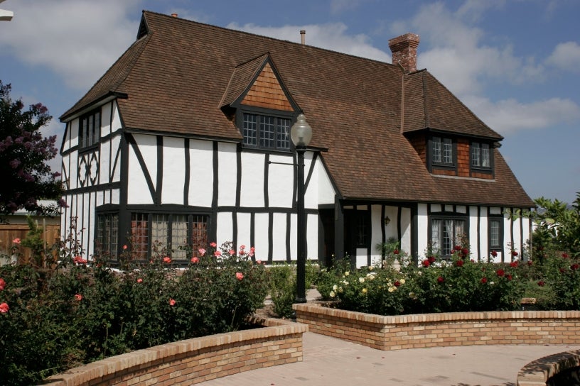 english style cottage white plaster brown wooden supports 2 stories