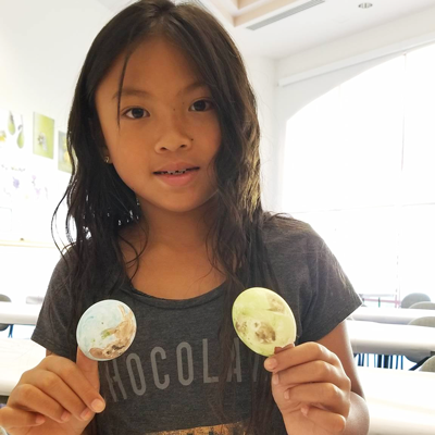 Image of a kid with two painted eggshells