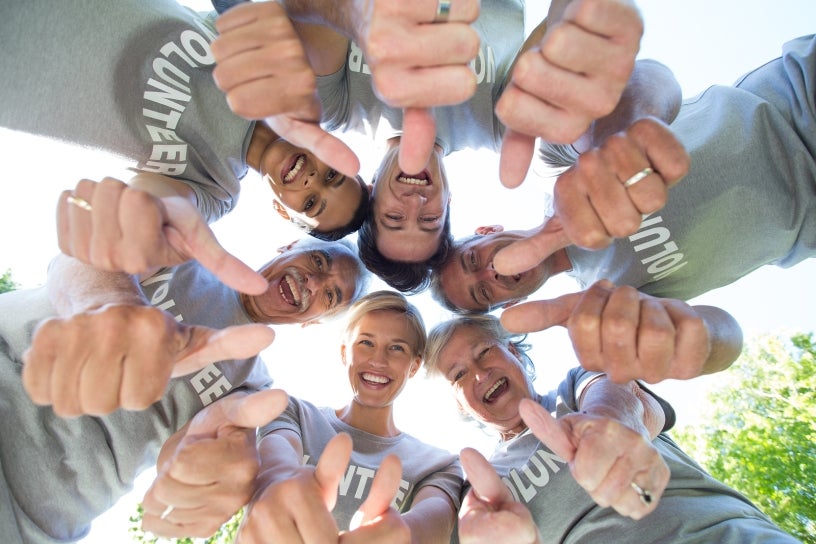 Photo of happy volunteer family looking down with thumbs up on a sunny day