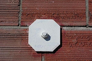 Steel bolts tie the unreinforced masonry walls to the floor of a building.