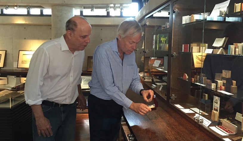 Photo of reporter Ken Kramer and Special Collections librarian Rick Crawford examining one of the world's smallest book.