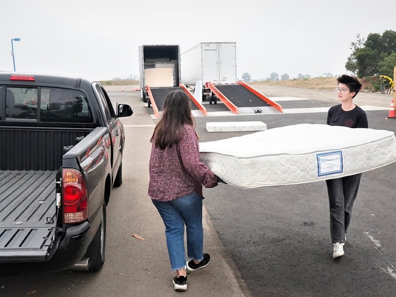 two people unloading a mattress from a truck