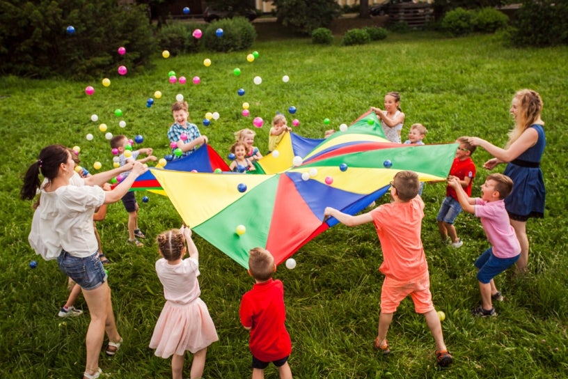 Kids and teachers playing with colorful tarp and balls