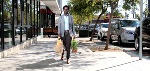 Pedestrian Walking with Groceries on Sidewalk