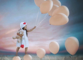Photograph of a little girl holding balloons and a teddy bear by artist Nathaly Alvizures.