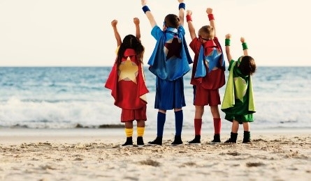 Kids in superhero costumes at the beach