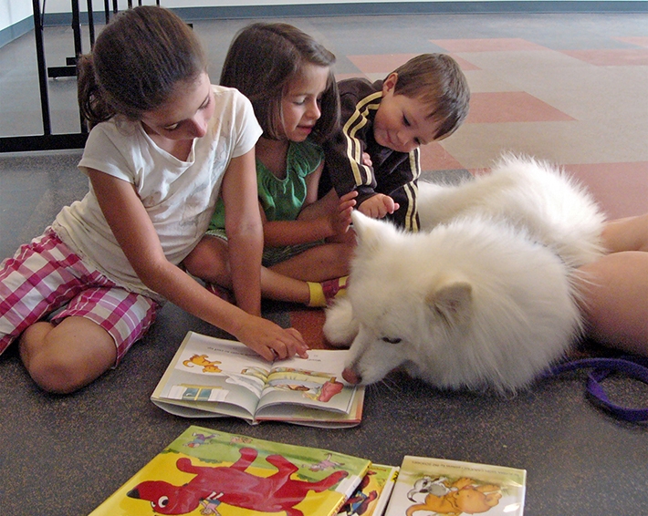 Erin Gillum reads to dog Bitsy with sister Sidney and brother Garrett