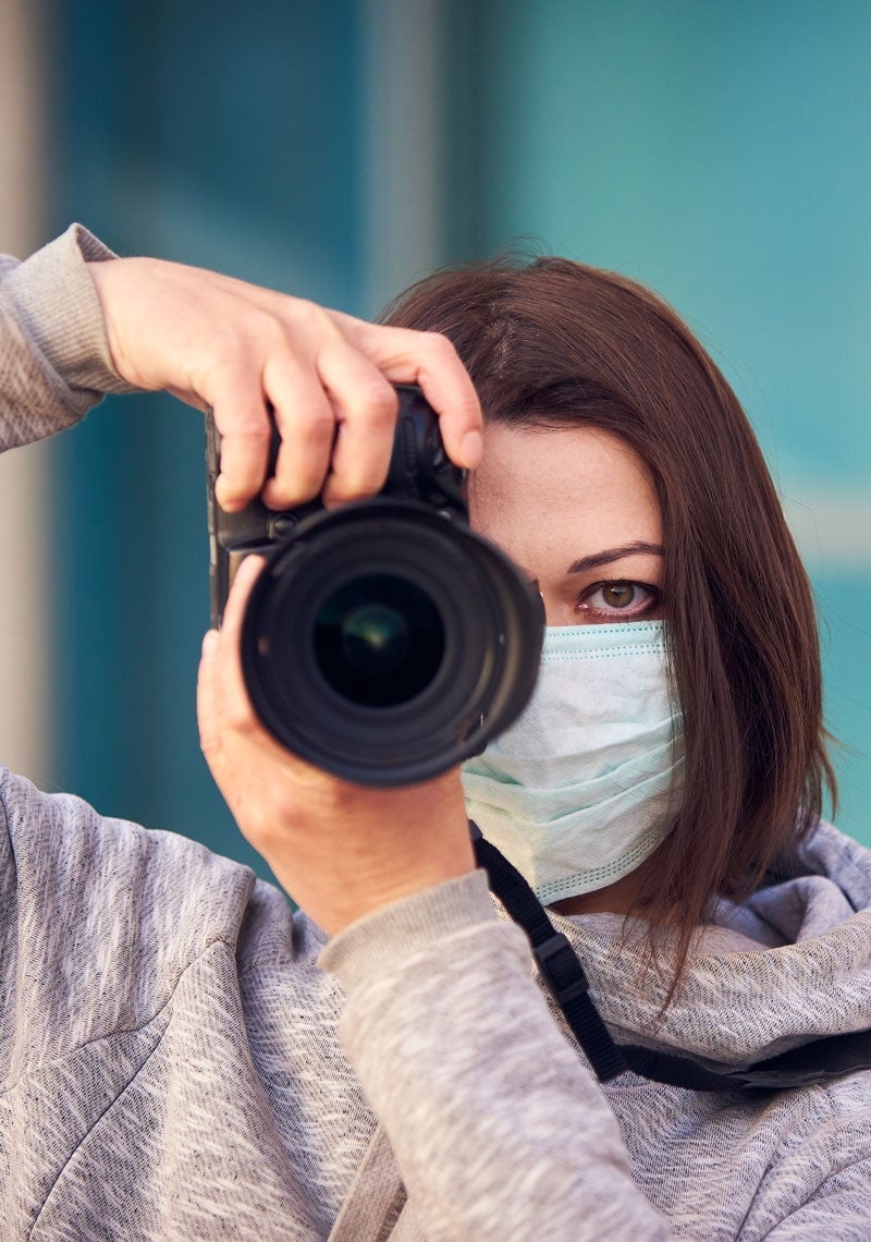 Woman wearing a mask with a camera taking a picture