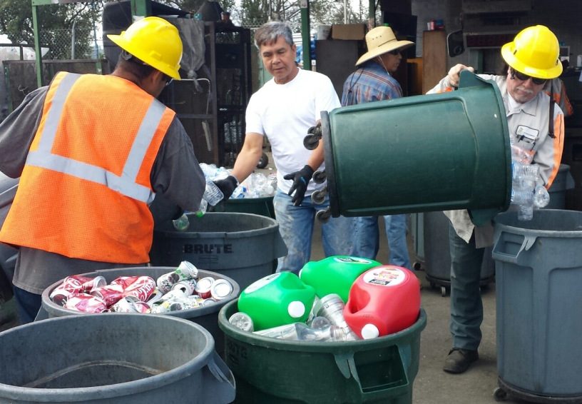 Several men sorting items into bins for recycling