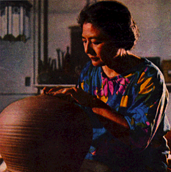 Color portrait of Toshiko Takaezu molding pottery at her spinning wheel.