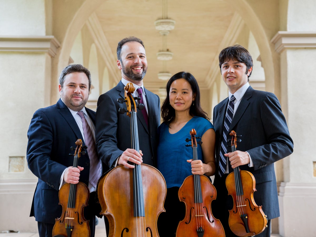 Photo of Hausmann Quartet under an arch holding instruments