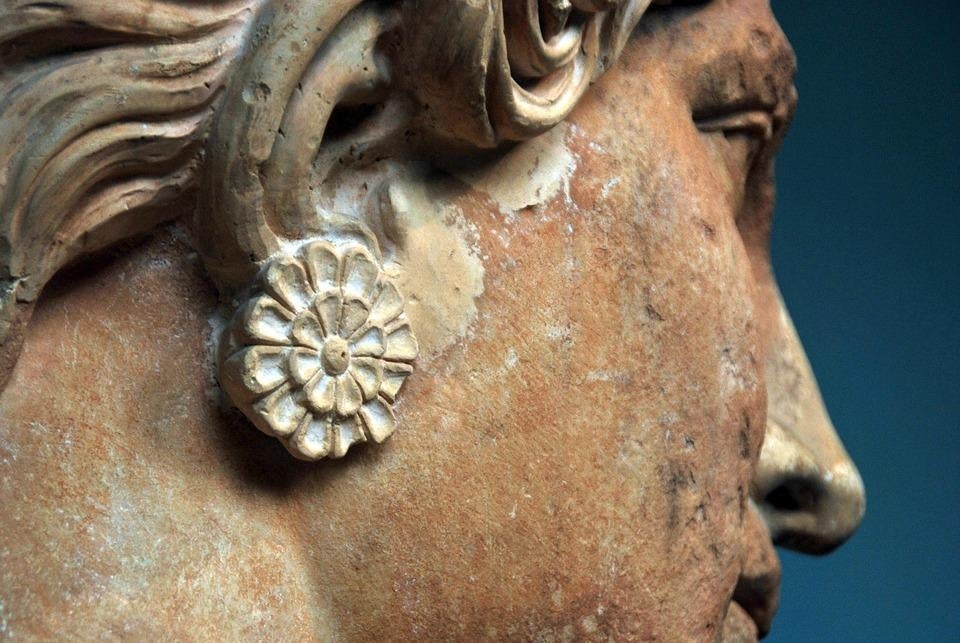Close up photograph of an earring detail on a fading and aged statue