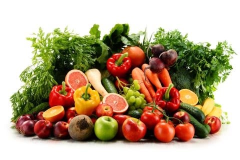 Bunch of fruits vegetables in vibrant colors piled high including herbs, apples, grapefruit, carrots, peppers, tomatoes, and cucumbers
