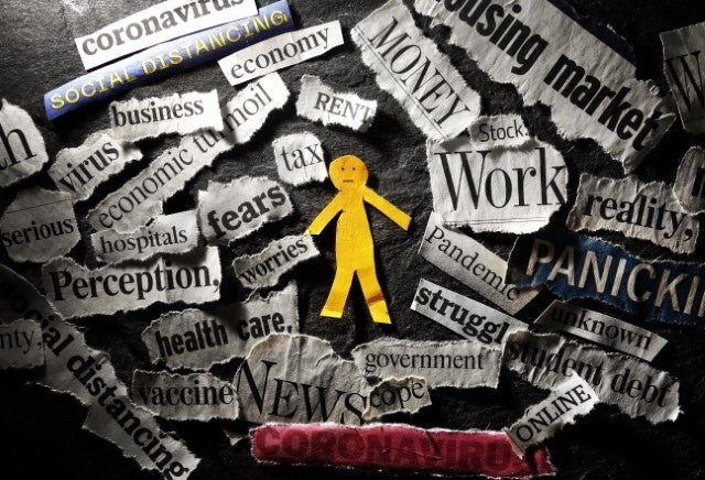 Paper cutout of person looking overwhelmed surrounded by clips of newspaper headings