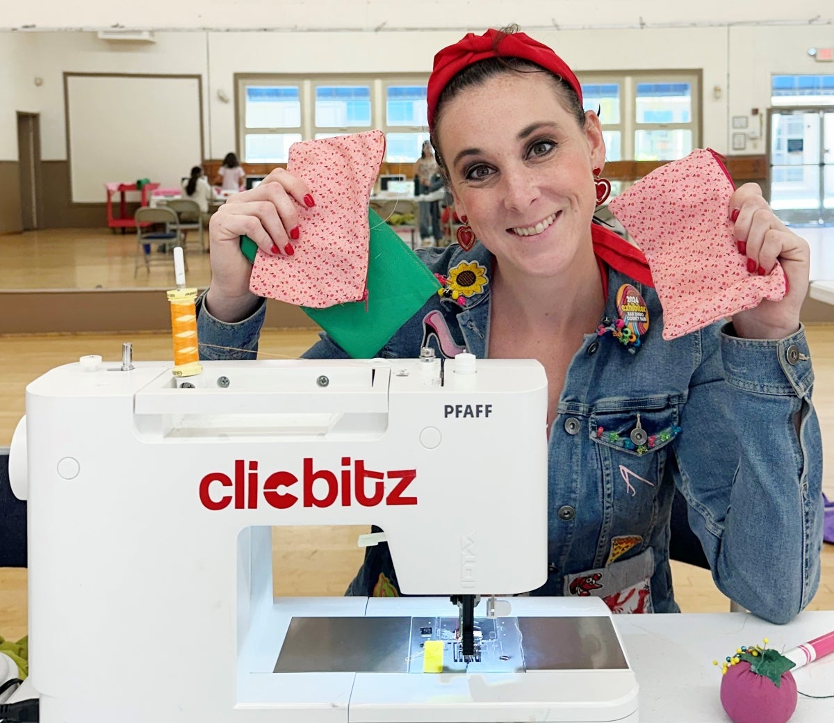 Woman holding zipper pouches with sewing machine.