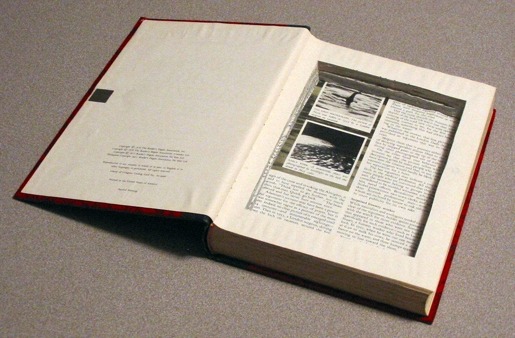 An open book with a large rectangle cut out of the center of most of the pages.