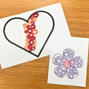 Heart and flower outlines decorated with colorful spirals made out of paper.