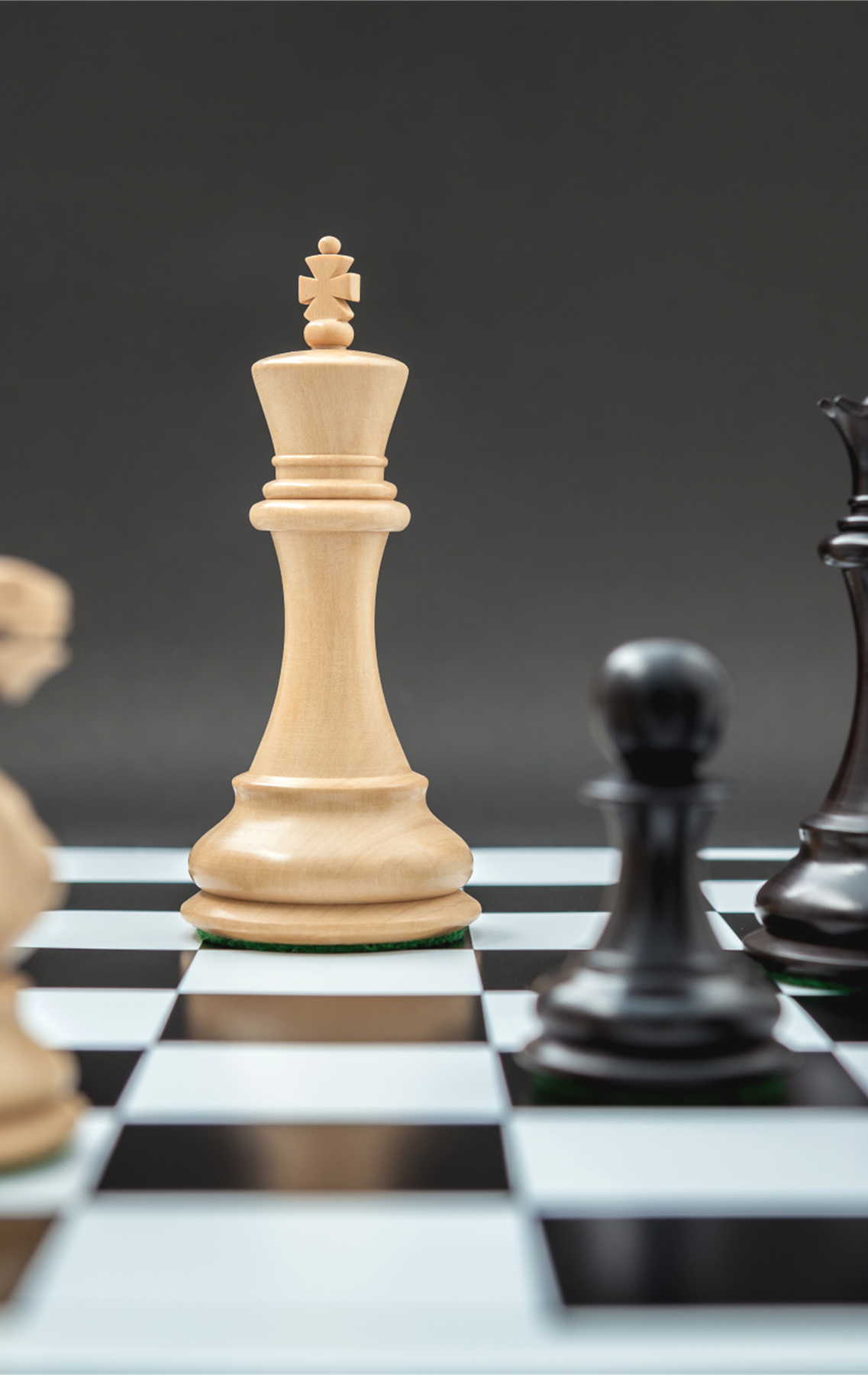 A close up of chess pieces on a chessboard with the focus on the white knight, white king, black pawn and black queen.