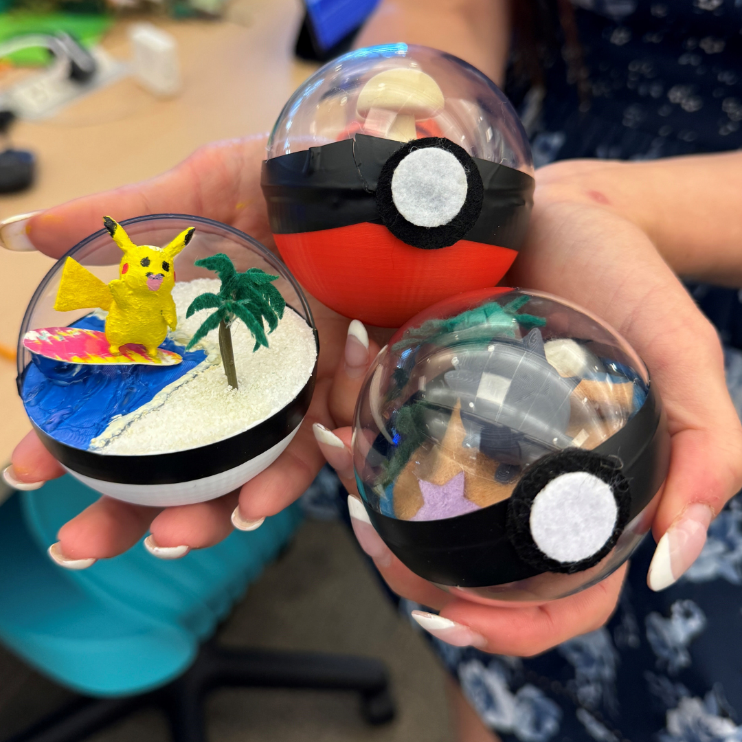  Close-up of a person holding three hand-made pokéballs with little scenes inside like a surfing Pikachu.