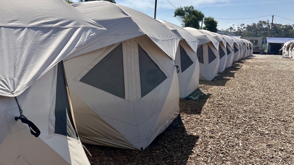 A row of tan-colored tents is lined-up inside of the City's O Lot Safe Sleeping site.