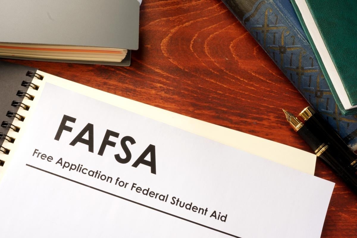 Notebook with "FAFSA" printed at the top of the page, on a desk next to books and a pen
