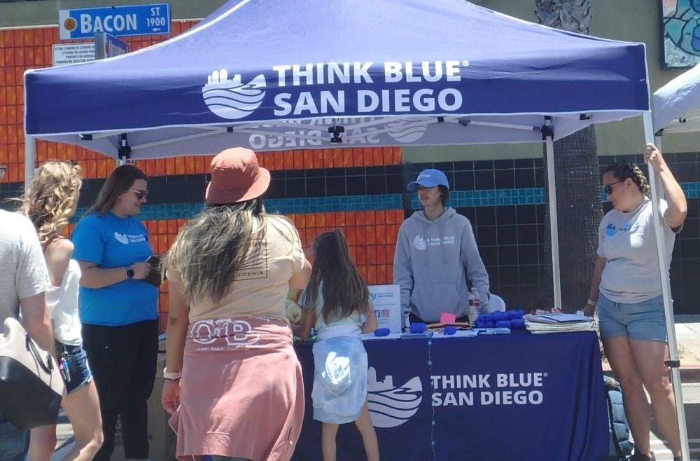 City staff host a Think Blue pop up under a blue canopy and are engaging community members