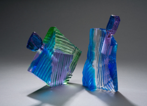 Two iridescent blue, green, and purple angular glass perfume bottles