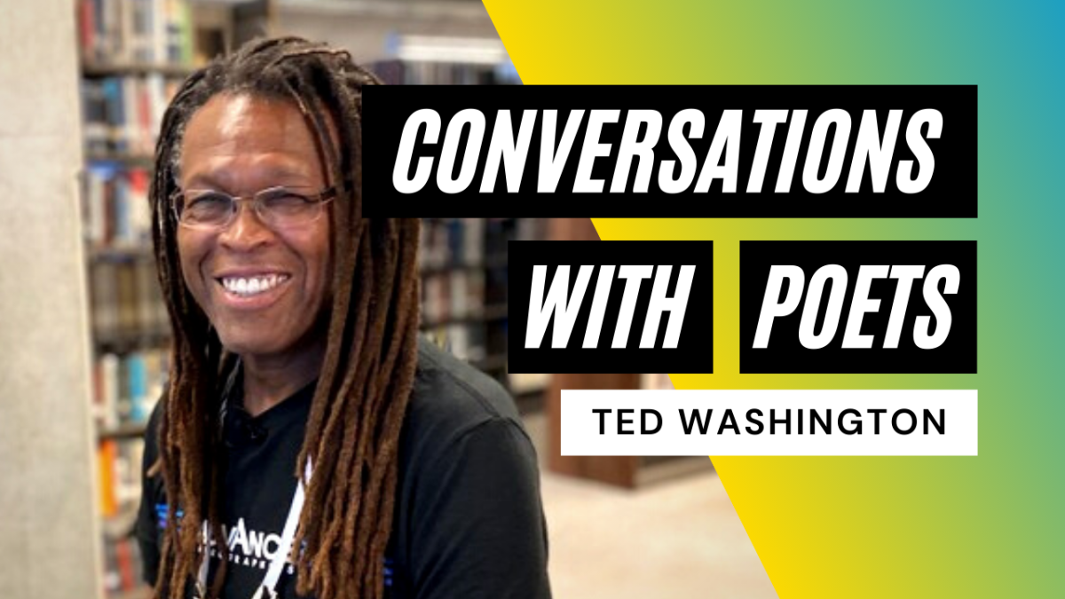 An older Black man with dreadlocks and glasses smiles with library shelving in the background.